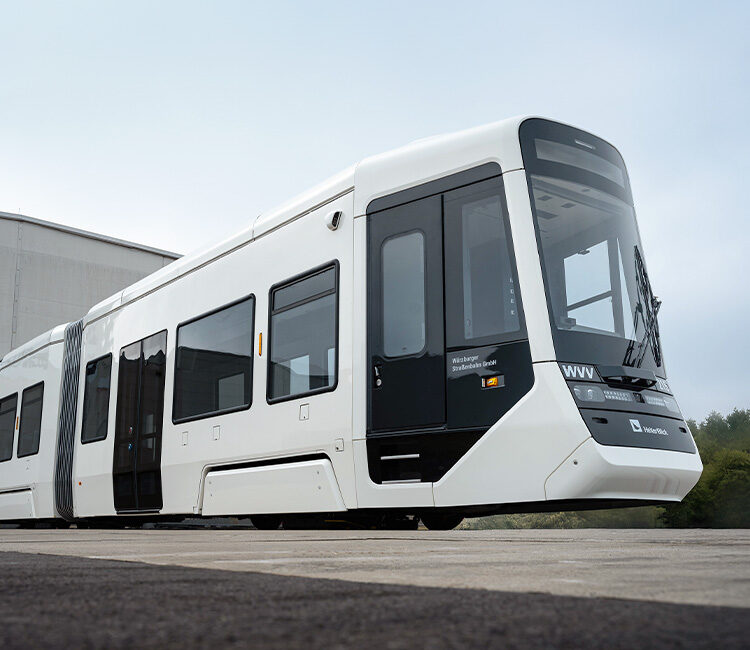 Eine weiße Straßenbahn kommt aus einer Werkshalle gefahren – aus einer tiefen Perspektive fotografiert.